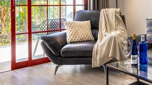 Un salon moderne avec un canapé en cuir, une table basse en verre, un lampadaire et une vue dégagée grâce à de grandes portes vitrées.