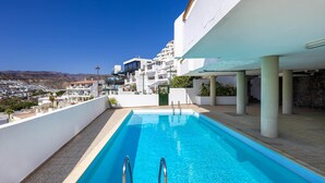 Una piscina amb vista a un poble situat en un turó i a les muntanyes.