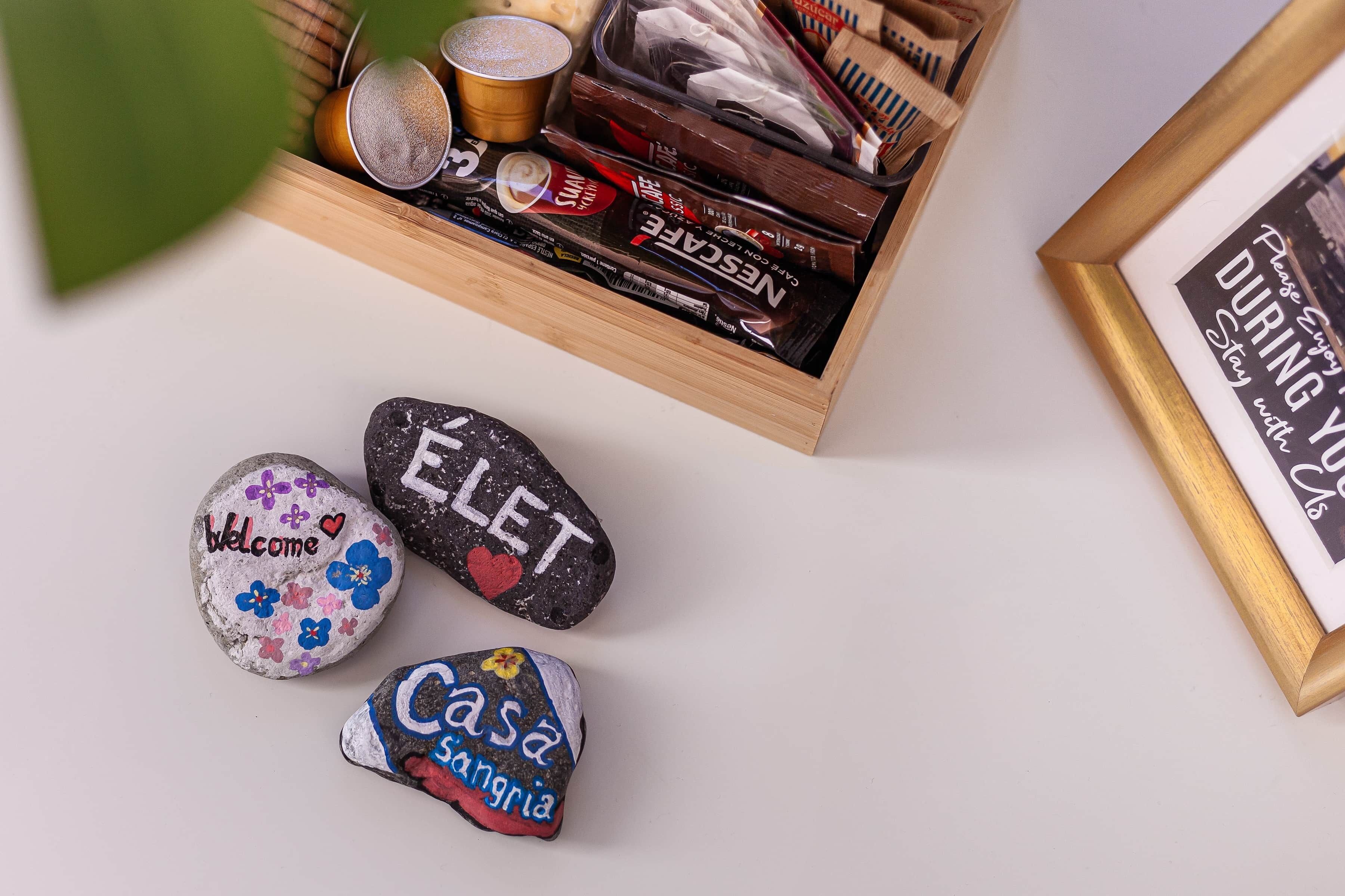 Una caja de madera con bombones, un cartel enmarcado y piedras pintadas con mensajes.