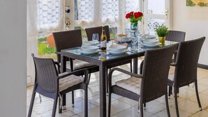 A dining area with a glass table, wicker chairs, and a view through large windows. - Paseo Suiza (Las Palmas)
