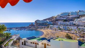 Un complejo turístico frente al mar con villas privadas en la playa, un puerto deportivo y una extensión de arena.