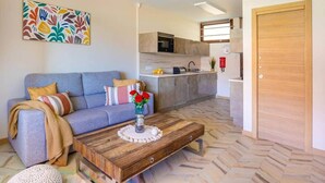 Una sala de estar con un sofá, una mesa de centro y una cocina al fondo.