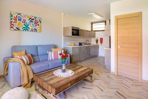 Ein Wohnzimmer mit einer Couch, einem Couchtisch und einer Küche im Hintergrund.