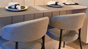 Un espace repas moderne comprenant deux chaises, une table et un objet décoratif en verre posé sur la table.