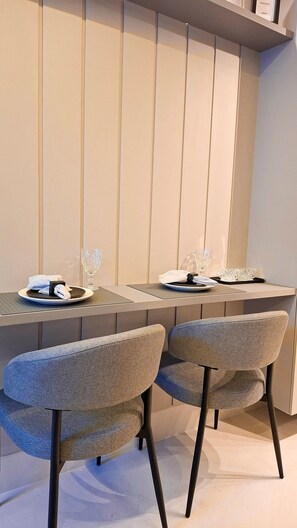 Ein moderner Essbereich mit zwei Stühlen, einem Tisch und einem dekorativen Glas darauf.