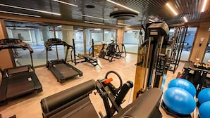Une salle de sport équipée de tapis de course, de vélos elliptiques et de poids libres.