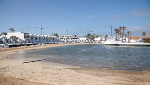 Un hotel fronte mare con file di camere, una spiaggia sabbiosa e un mare calmo.