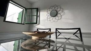 En matplats med ett glasbord, stolar, en skål och en spegel som hänger på väggen.