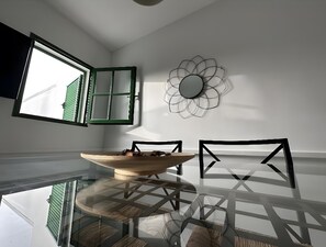 Un comedor con una mesa de vidrio, sillas, un tazón y un espejo en la pared.