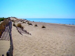 A sandy beach with a wooden fence and sparse vegetation. - L’Olivaie • Villa 8 pers piscine & jardin (Caveirac)