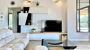 Ein modernes Wohnzimmer mit einer Couch, Fernseher und Zierpflanzen.