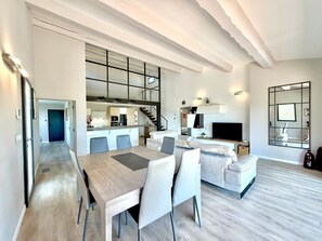 A modern apartment with a dining area, kitchen, living room, and a staircase. - L’Olivaie • Villa 8 pers piscine & jardin (Caveirac)