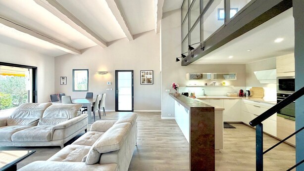 Ein modernes Wohnzimmer mit Sofa, Essbereich und einer Küche mit einer großen Kochinsel.