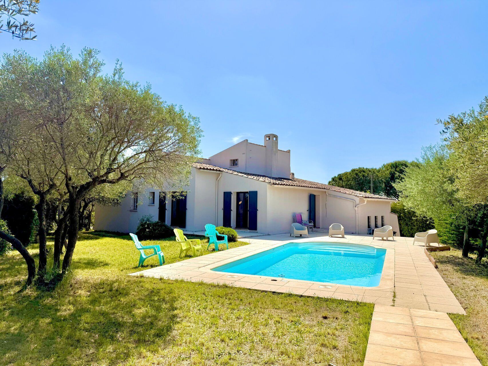 A house with a swimming pool, outdoor seating, and a garden.