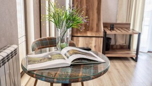 A round glass table with a plaid chair, a book, and a vase with flowers. - Gold Tower in Mestia (Mestia)
