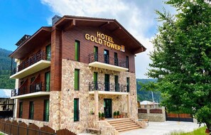 A multi-story hotel with a stone facade, balconies, and a sign reading 'HOTEL GOLD TOWER.' - Gold Tower in Mestia (Mestia)
