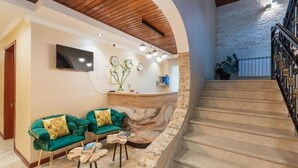 A reception area with a stone wall, a staircase, and a flat-screen TV mounted on the wall. - Gold Tower in Mestia (Mestia)
