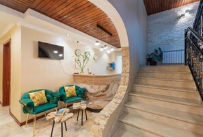A reception area with a stone wall, a staircase, and a flat-screen TV mounted on the wall. - Gold Tower in Mestia (Mestia)