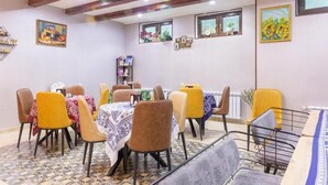 A dining area with tables and chairs, a tiled floor, and artwork on the walls. - Gold Tower in Mestia (Mestia)