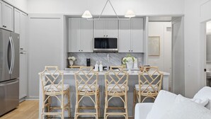 Eine moderne Küche mit Kochinsel, Barhocker und Kühlschrank.