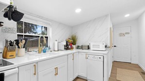 Una cucina moderna con mobili bianchi, forno a microonde integrato e una finestra vista.