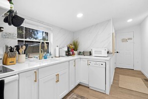 Une cuisine moderne avec des meubles blancs, un four à micro-ondes encastré et une fenêtre offrant une belle vue.