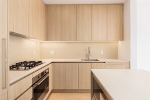 Une cuisine moderne avec des meubles en bois, des appareils électroménagers en acier inoxydable et un plan de travail blanc.