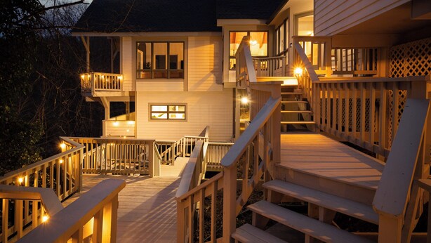 Ein zweistöckiges Holzhaus mit einer Terrasse, Treppe und Veranda.
