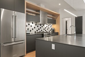 Een moderne keuken met een vast kookeiland, roestvrijstalen apparatuur en een honingraatachterwand.