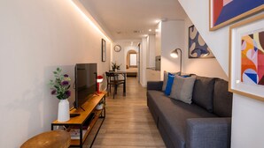 A modern living room with a sofa, TV, and a dining area with a table and chairs. - The Bica Secret Nest by LovelyStay (Lisboa)