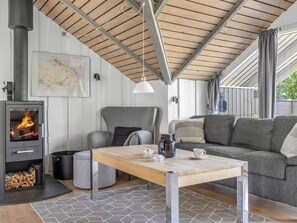 Ein gemütlicher Wohnbereich mit Kaminofen, einer Couch, einem Tisch mit Tassen und einer Karte an der Wand.