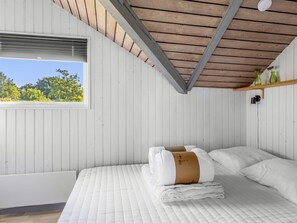 Ein Schlafzimmer mit einem Bett, einem Fenster und einer Holzbalkendecke.