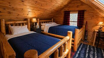 A cabin with two wooden beds, a desk, and a chair.