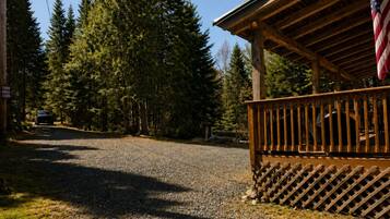 Une cabane avec une allée en gravier, entourée de grands arbres.