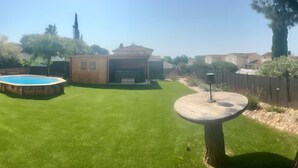 En baghave med swimmingpool, træterrasse og et hegn.