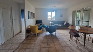 En opholdsstue med sofa, stole, fjernsyn og spisebord.
