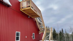 A red building with a wooden staircase leading to a balcony. - MBA- New Apt w/Direct Access Snowmobile/ATV Trail (Presque Isle)