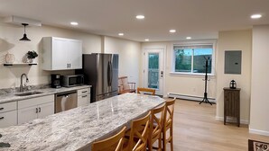 A modern kitchen with granite countertops, stainless steel appliances, and wooden chairs. - MBA- New Apt w/Direct Access Snowmobile/ATV Trail (Presque Isle)