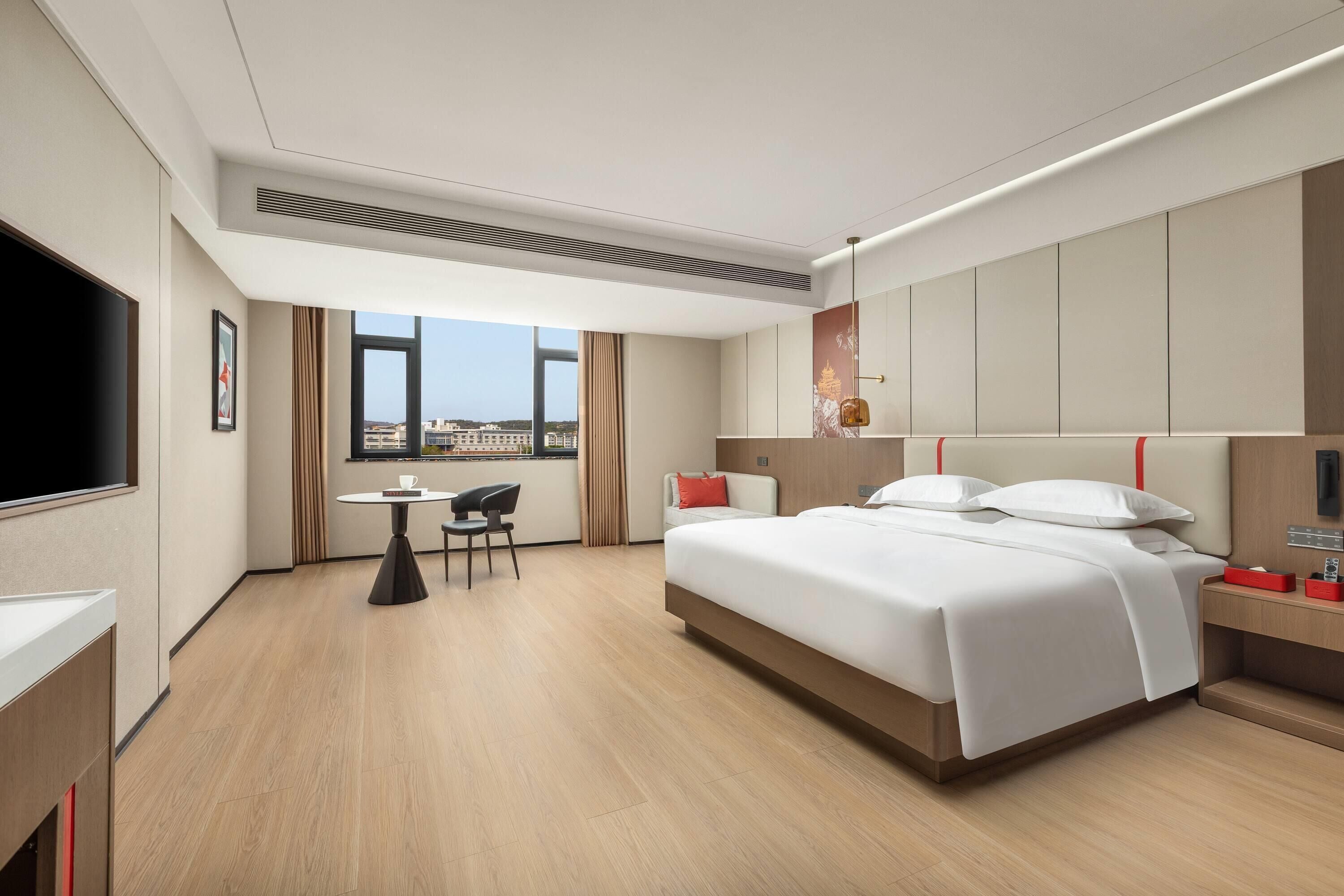 Una habitación de hotel moderna con una cama grande, un escritorio, una silla y una televisión.