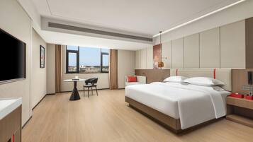 Una habitación de hotel moderna con una cama grande, un escritorio, una silla y una televisión.