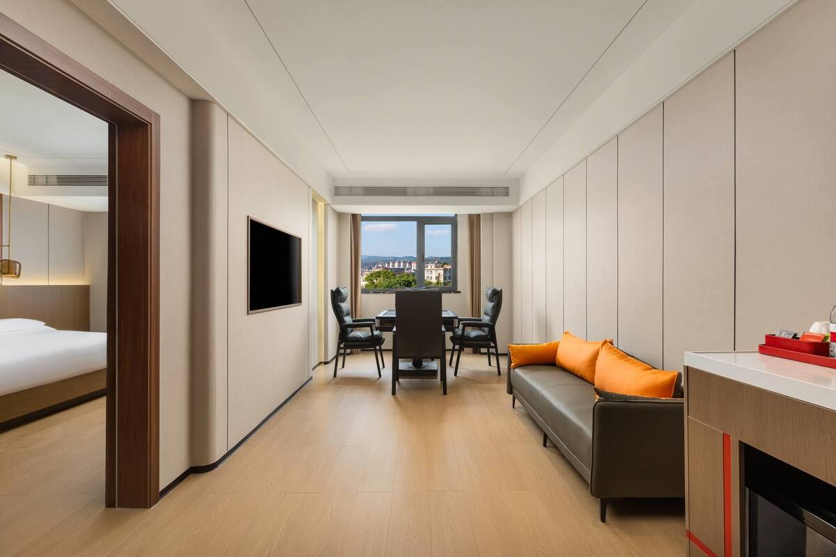 Una habitación de hotel moderna con comedor, sofá y televisor.
