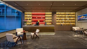 A modern lobby with a reception desk, seating area, and a large window.
