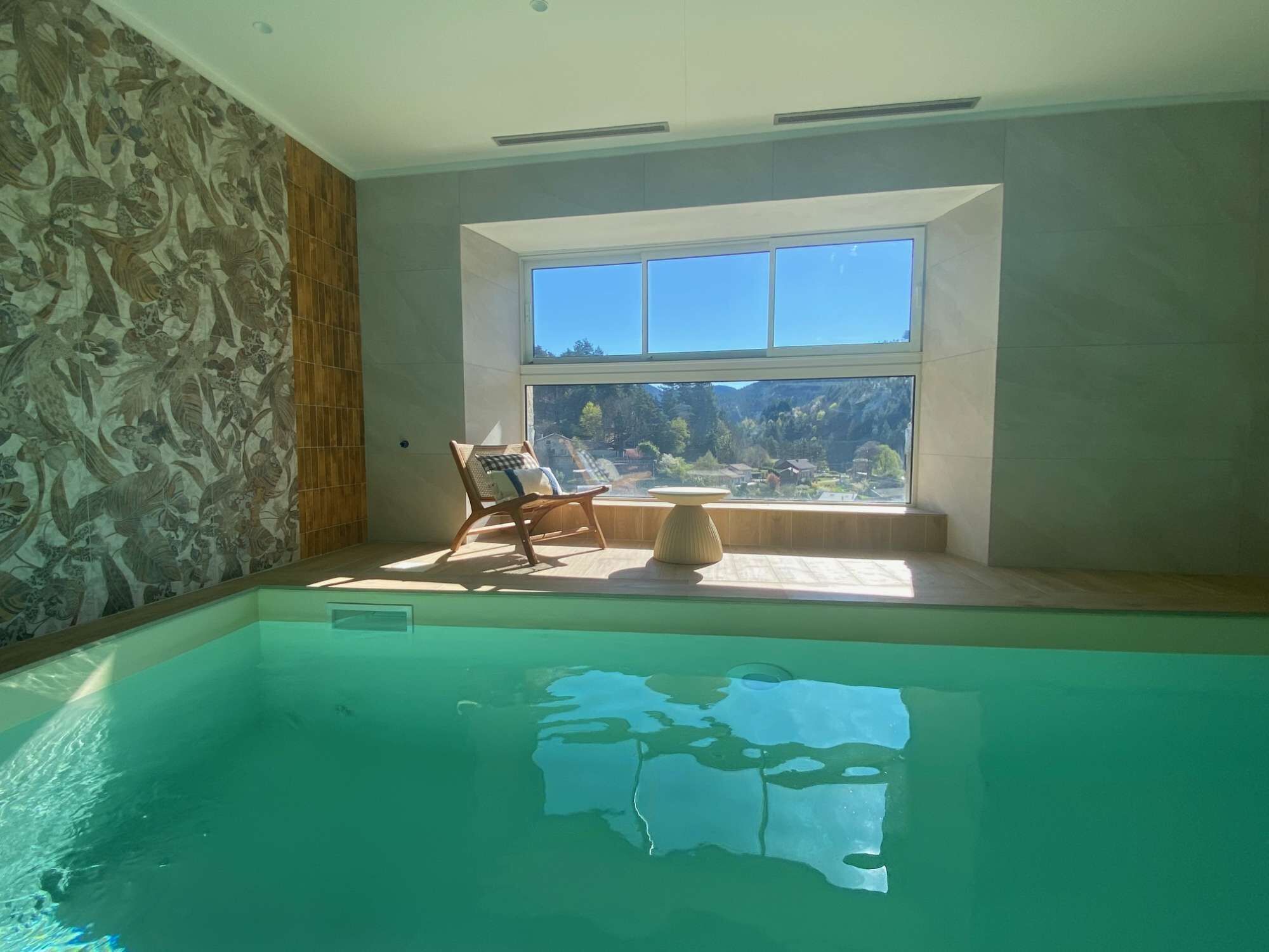 A swimming pool with a view of a mountainous landscape through a large window.