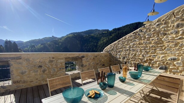 A table set outdoors with stone walls and a mountainous backdrop.