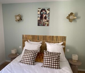 A bedroom with a checkered pillow set, a wooden headboard, and a wall-mounted painting. - Les murmures de l'Eyrieux, a holiday cottage for 15 people with an indoor swimming pool (Saint Martin de Valamas)
