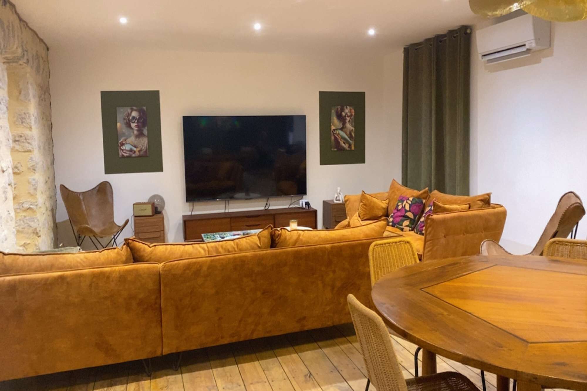 Una sala de estar con sofá, televisión, mesa de comedor y una silla.