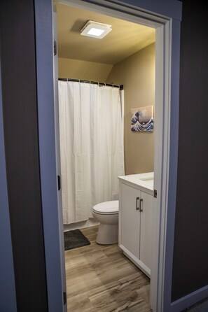 Een badkamer met toilet, douchegordijn, wastafel en kastje.