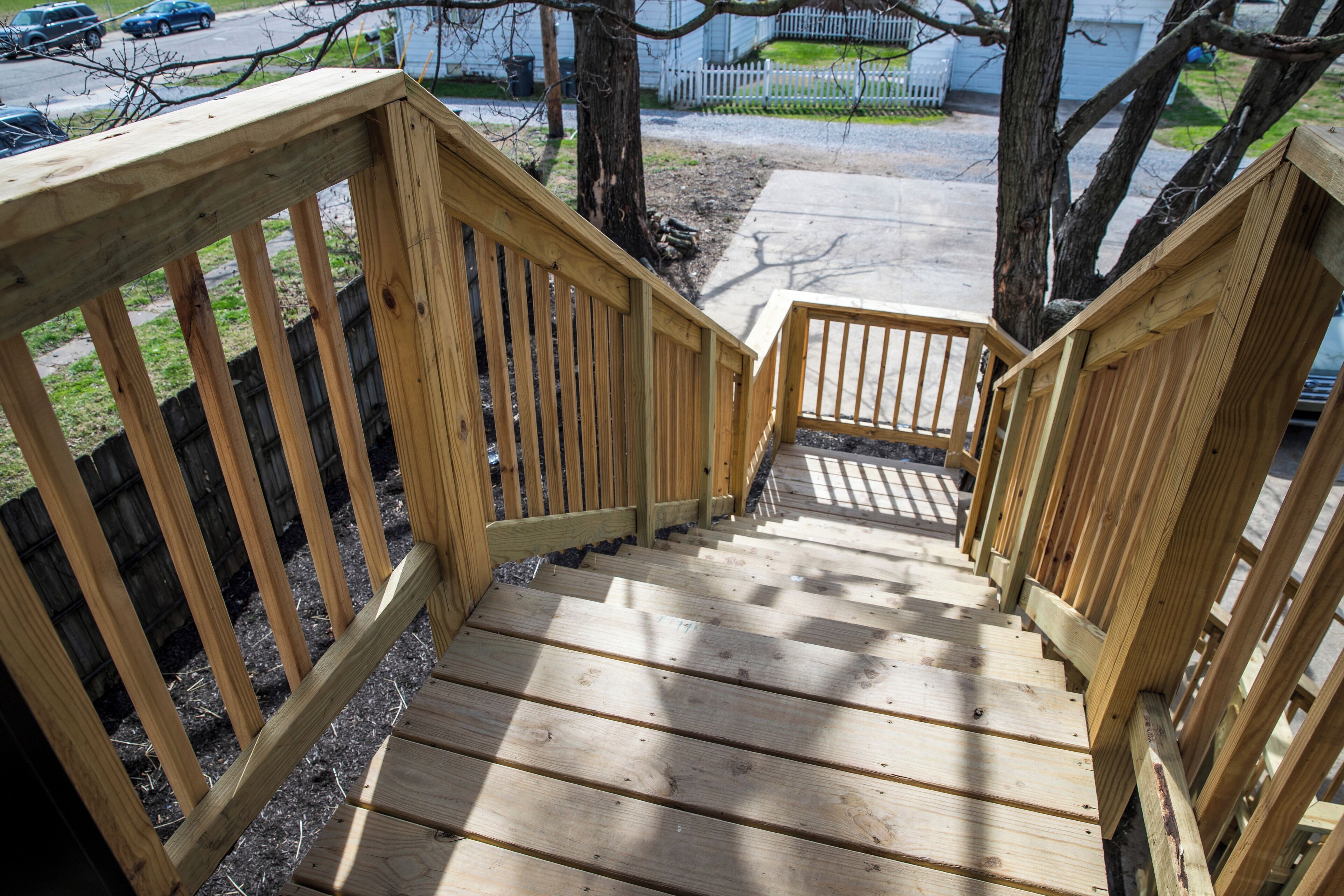 A wooden staircase leading down to a driveway.