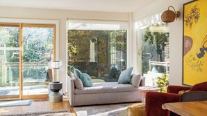 A modern living room with a sofa, a table, and a lamp. - Woodstock Waterfall Hideaway · Walk To Tinker St! (Woodstock)
