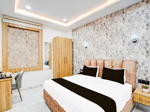 A bedroom with a bed, wooden wardrobe, bedside table, and a desk with a chair.
